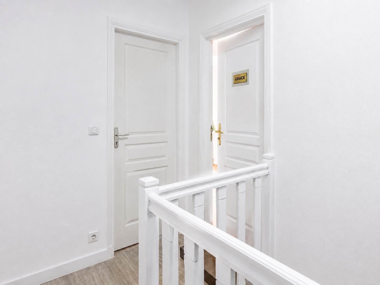A white door with a brass handle and a sign that reads 'GRACE.'
