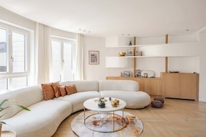 A modern living room with a large L-shaped sofa, a round coffee table, and a wooden floor. - Luxury & spacious near Accor Arena & Bastille (Charenton-le-Pont)