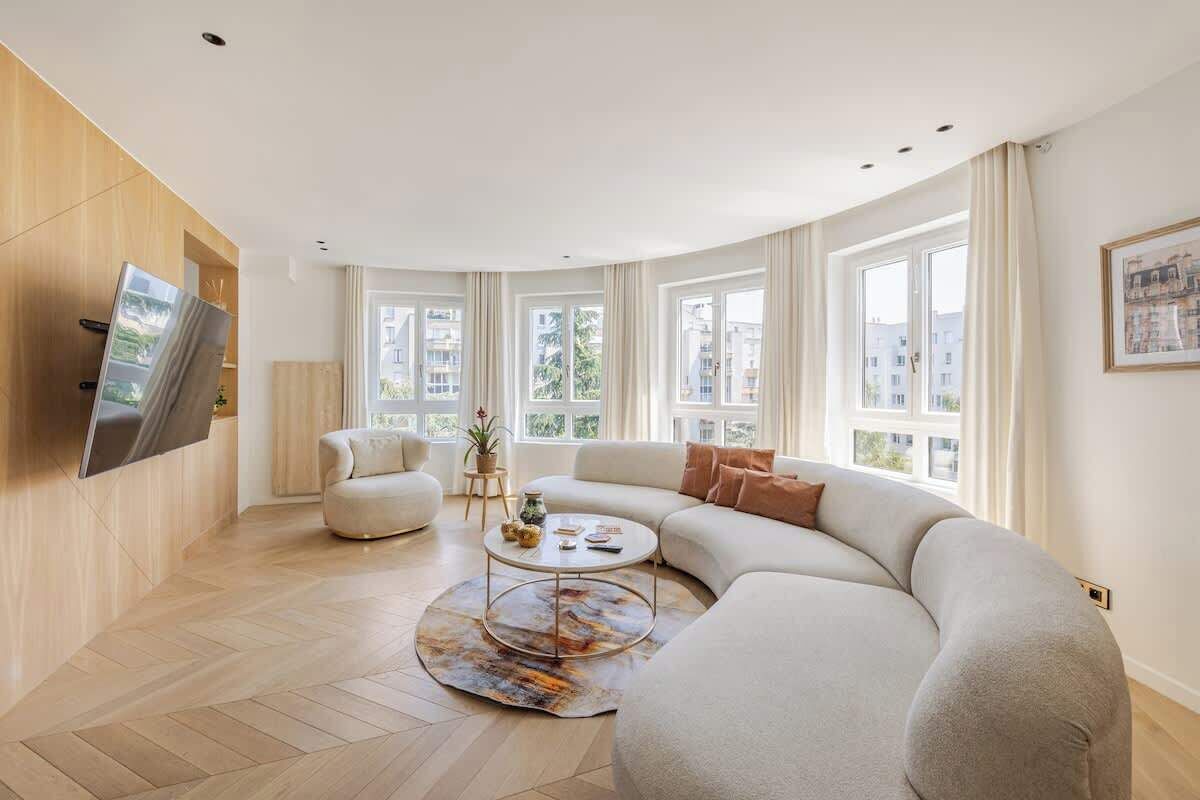 Ein modernes Wohnzimmer mit einer gebogenen Couch, einem runden Couchtisch und einem flachbildfernseher an der Wand.