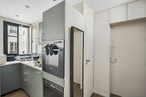 A modern kitchen with a built-in oven, a microwave, and a sink. - Fully Equipped Studio – Concorde – Mobility Lease (Paris)