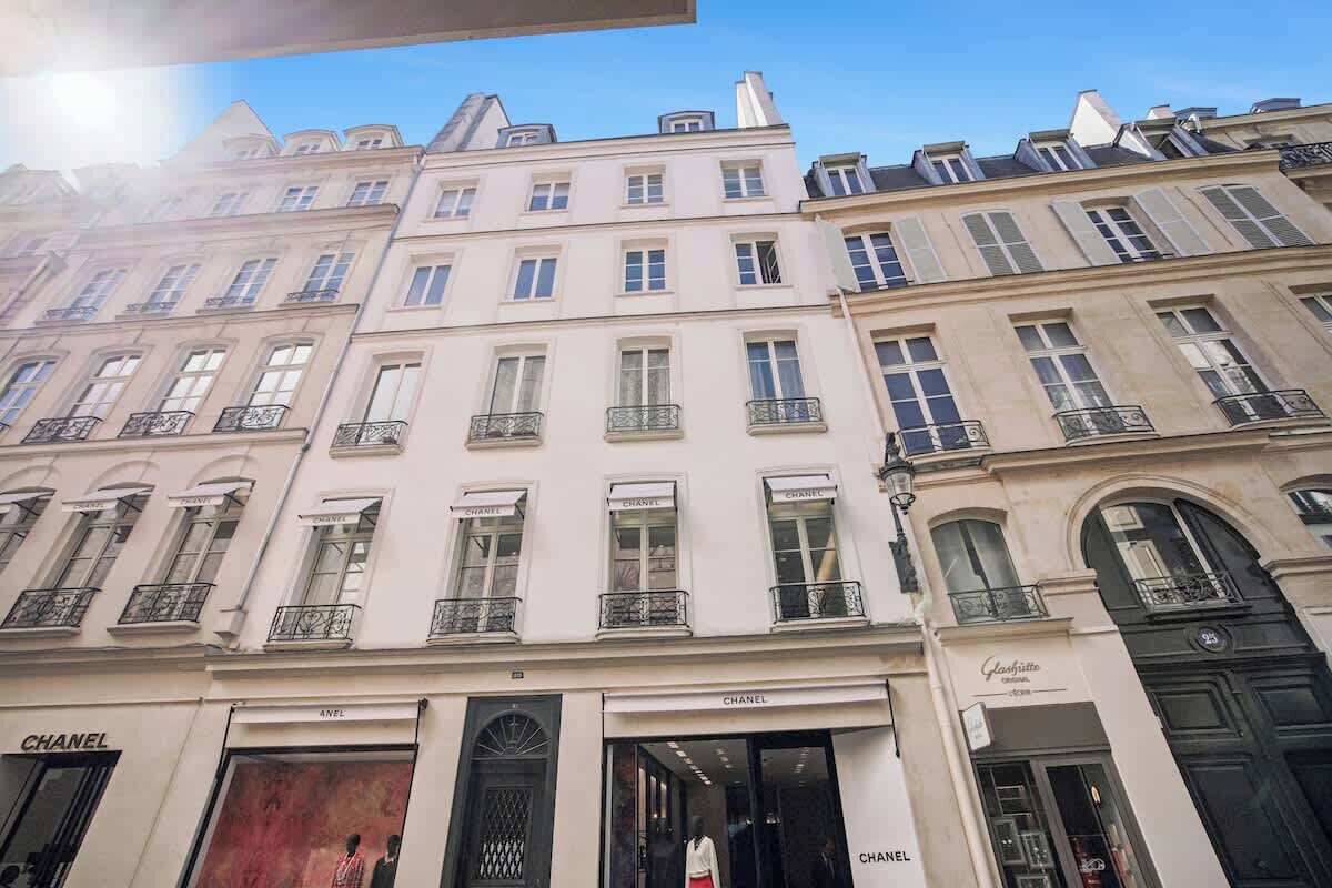 Une rangée de bâtiments de style européen classique, dotés de façades à plusieurs étages et présentant des devantures de magasins bien visibles, avec des enseignes.