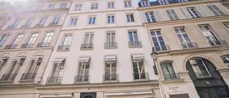 Une rangée de bâtiments de style européen classique, dotés de façades à plusieurs étages et présentant des devantures de magasins bien visibles, avec des enseignes.