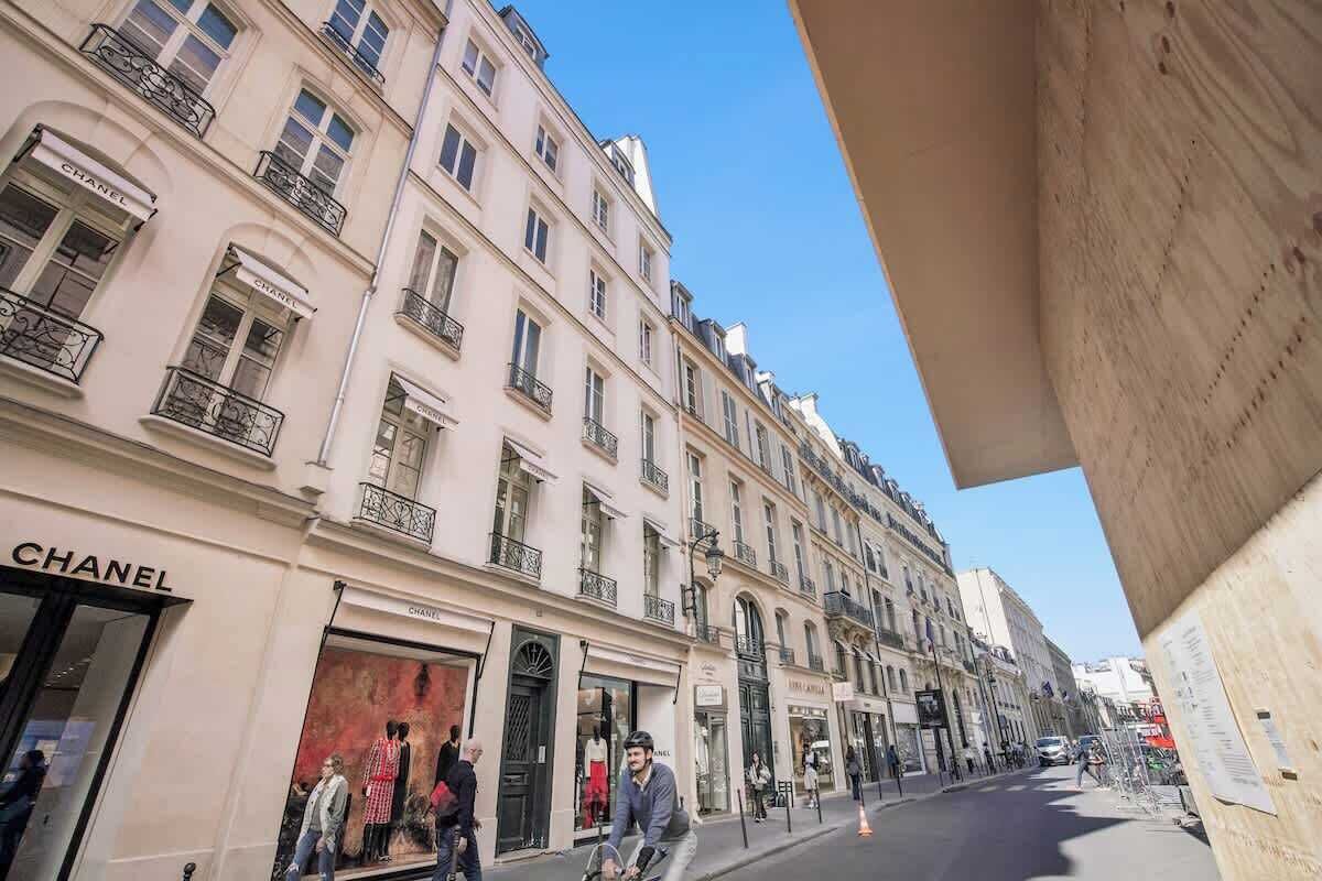 Une vue de rue avec une boutique Chanel, des piétons et une architecture européenne classique.