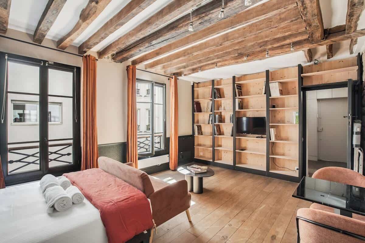 Une chambre d’hôtel comprenant un lit, un coin salon, une télévision et une bibliothèque.
