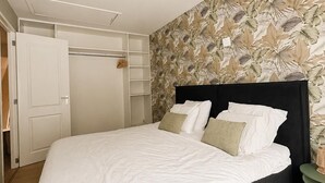 A bedroom with a bed, a wardrobe, and a wall with a leaf pattern. - Historic Stay in Medemblik | Tesstays (Medemblik)