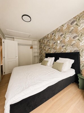 Ein Schlafzimmer mit einem Bett, einem Kleiderschrank und einer Wand mit Blattmuster.