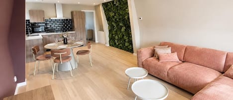 A modern living room with a sofa, round coffee table, and dining area with chairs.