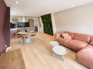 Ein modernes Wohnzimmer mit einer Couch, einem runden Couchtisch und einem Essbereich mit Stühlen.