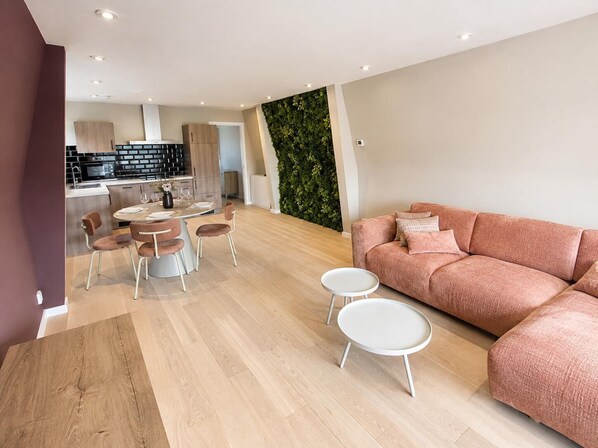 A modern living room with a sofa, round coffee table, and dining area with chairs.