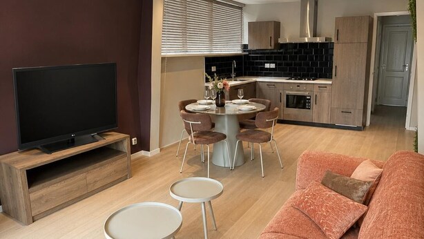 A modern living room with a large sofa, a TV, and a dining area with a table and chairs. - Historic Stay in Medemblik | Tesstays (Medemblik)