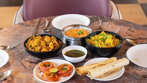 A table with various dishes, including rice, a bowl of soup, and a plate of sliced onions.