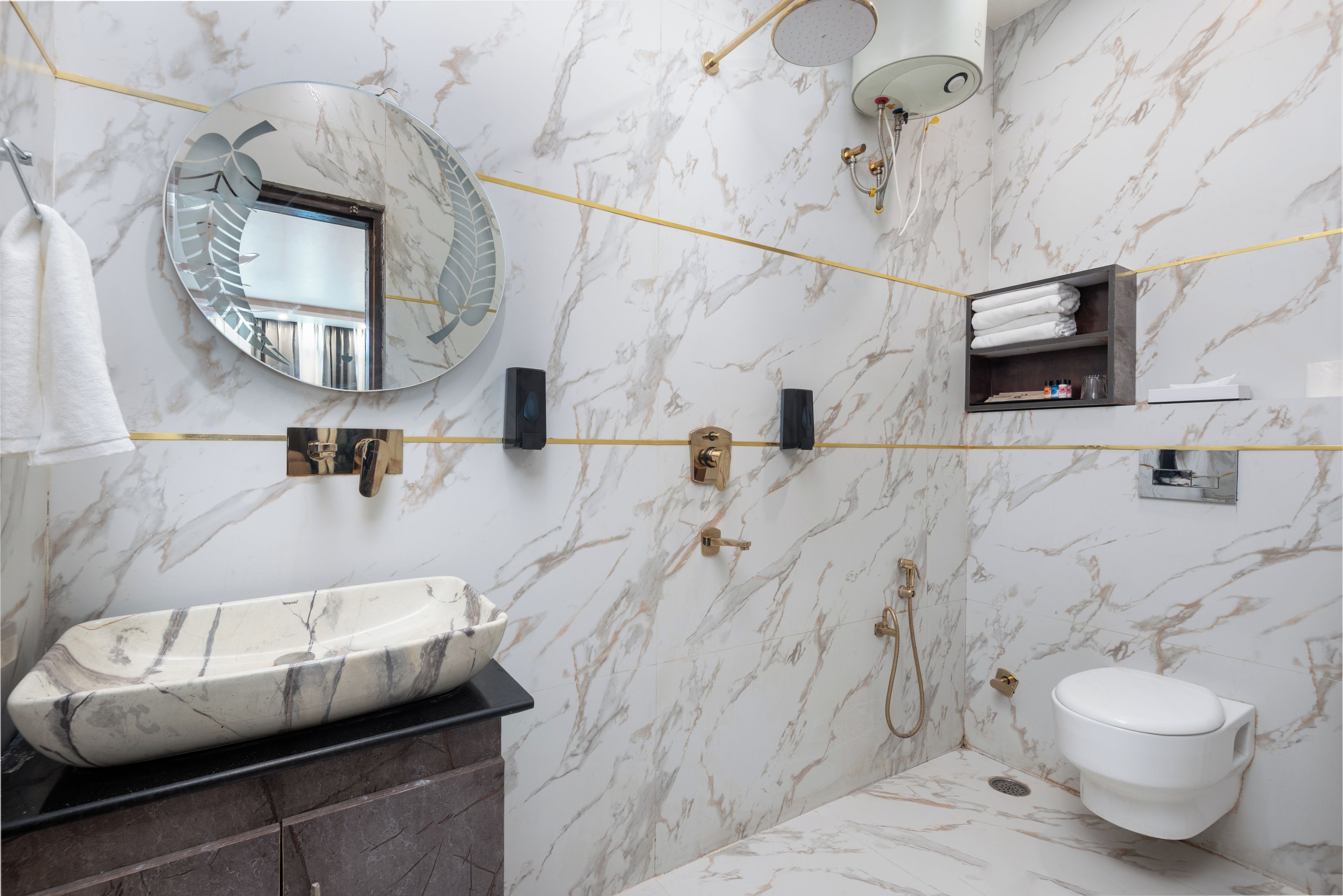 A bathroom with a marble vanity, a round mirror, a toilet, and a shower area.