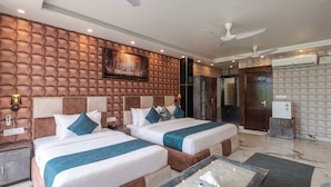 A hotel room with two beds, a large painting, a ceiling fan, and a marble floor.
