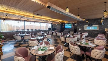 En restaurant med et skakternet gulv, runde borde og polstrede stole.