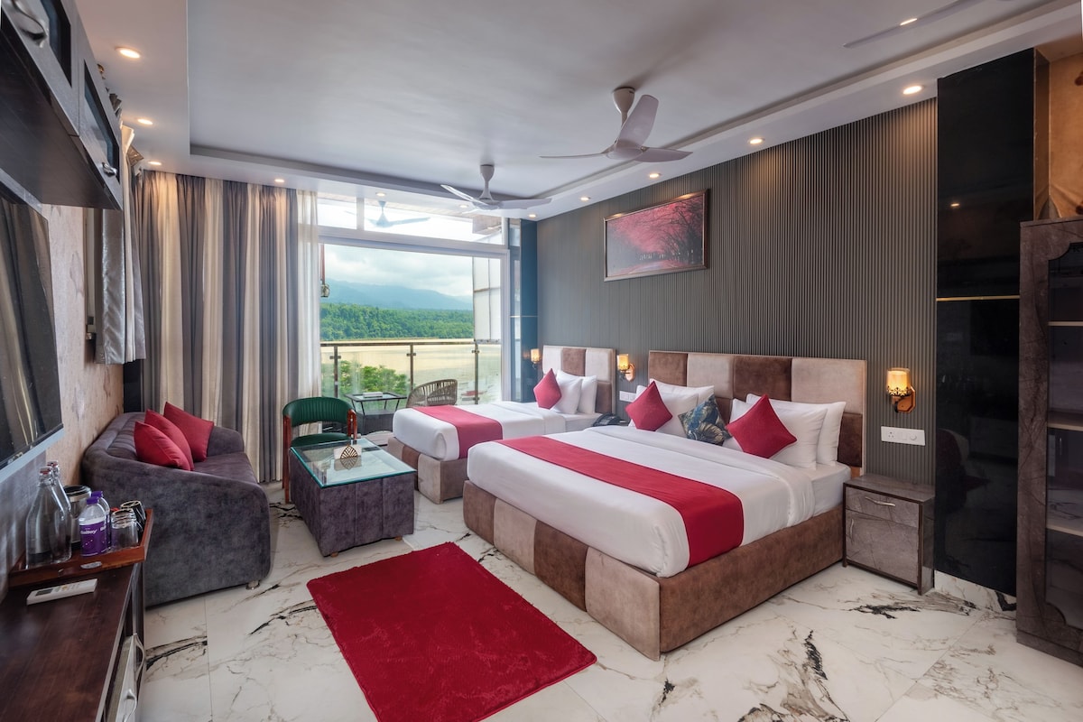 Habitación de hotel con una cama grande, un sofá, una mesita y vistas al exterior.