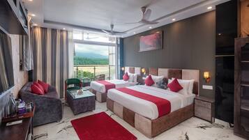 A hotel room with a large bed, a sofa, a small table, and a view of the outdoors.