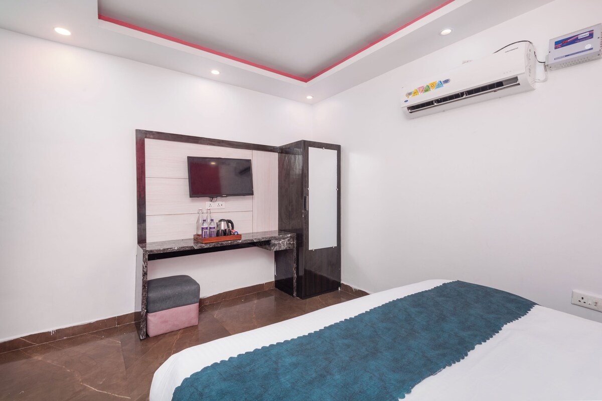 Un dormitorio moderno con cama, televisor, escritorio y aire acondicionado.