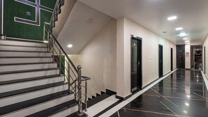 A hotel corridor with a staircase, doors, and a polished floor.