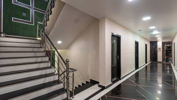 A hotel corridor with a staircase, doors, and a polished floor.