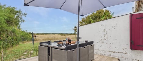 An outdoor patio with a table and chairs, a large umbrella, and a view of the countryside.