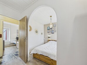 A bedroom with a wooden bed, a white door, and a hallway leading to another room. - House with pool & large garden overlooking horses (Angles)