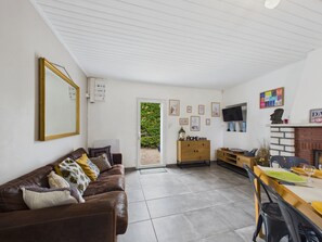A living room with a brown leather sofa, a wooden cabinet, a dining table with chairs, and a fireplace. - House with pool & large garden overlooking horses (Angles)