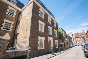 A street view of a brick building with multiple windows and a gated entrance. - Chic 1BDR City Retreat by Regents Park (Greater London)