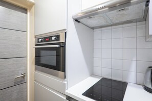 Eine Küche mit Einbauofen, Kochfeld und weißen Fliesenwänden.