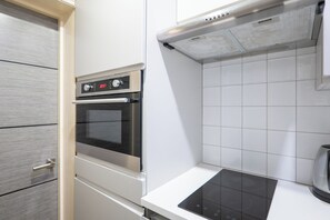 A kitchen with a built-in oven, a stovetop, and white tiled walls. - Chic 1BDR City Retreat by Regents Park (Greater London)