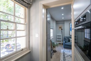 A hallway leading to a living area with a sofa, a plant, and a kitchen area with an oven. - Chic 1BDR City Retreat by Regents Park (Greater London)