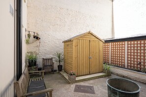 A wooden shed in a courtyard with a bench and potted plants. - Chic 1BDR City Retreat by Regents Park (Greater London)