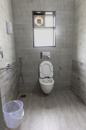 Un baño pequeño y moderno con inodoro, ducha y ventana.