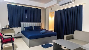 Habitación de hotel con cama, escritorio, silla, sofá y una pequeña mesa.