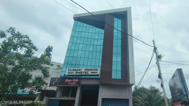 Un edificio moderno con un llamativo frente de vidrio, identificado como Hotel Rajdhani Premium.