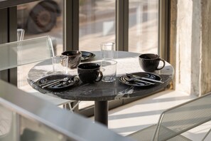 A round table with plates, cutlery, and black mugs. - Noctilia Athens (Athens)