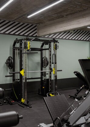 A gym with a squat rack, weight plates, and a bench press. - Noctilia Athens (Athens)