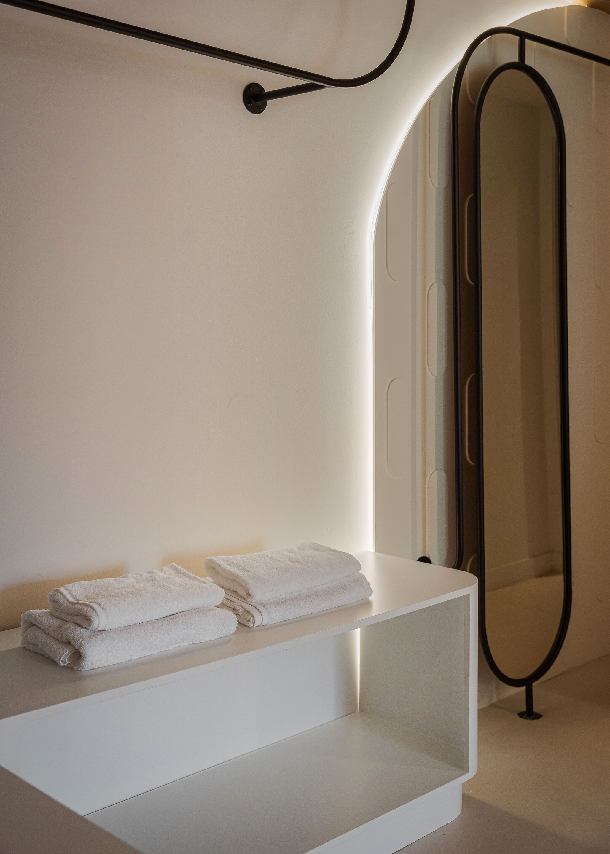 Un baño minimalista con tocador blanco, una toalla y un espejo grande.