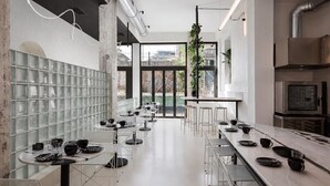 A modern kitchen with stainless steel appliances, a long dining table, and a glass block wall.