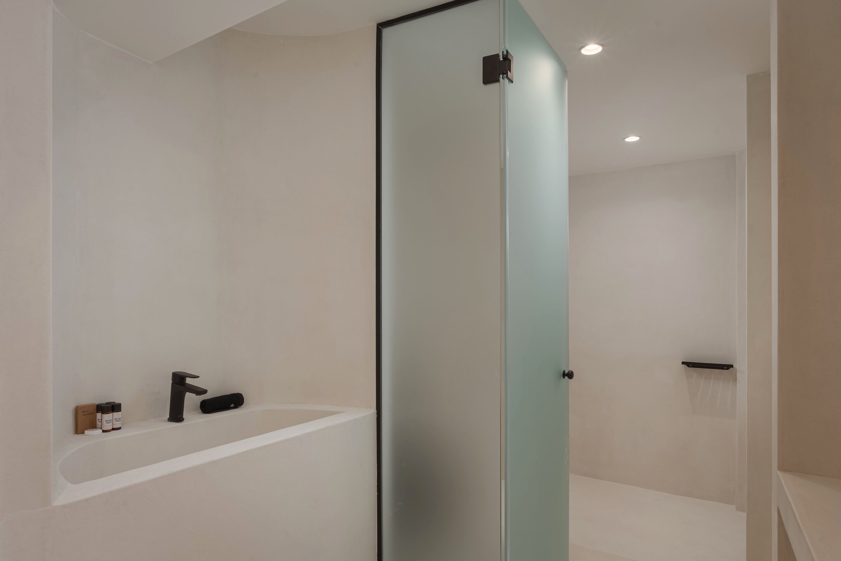 A modern bathroom with a glass partition, a white sink, and a black faucet.