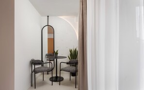 Un comedor moderno con una mesa redonda, cuatro sillas y un espejo alto.