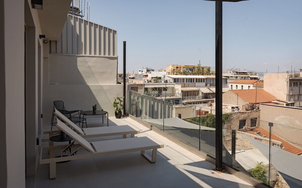 A modern balcony with a minimalist design, featuring a lounge chair, a small table, and potted plants. - Noctilia Athens (Athens)