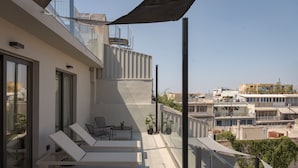 A modern balcony with a white lounge chair, a small table, and potted plants.
