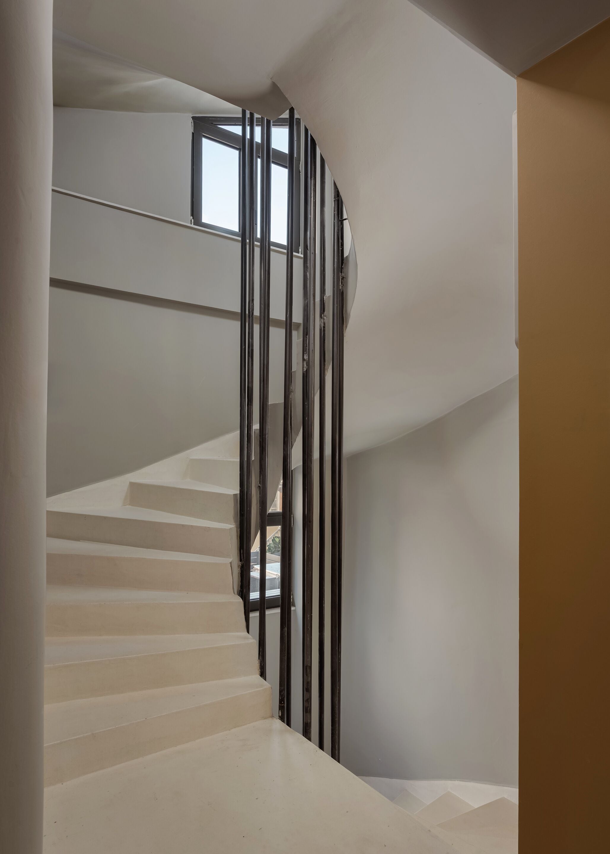 Una escalera de diseño moderno, con barandilla de cristal y vista al cielo a través de un ventanal.