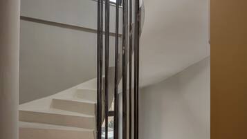 Una escalera de diseño moderno, con barandilla de cristal y vista al cielo a través de un ventanal.