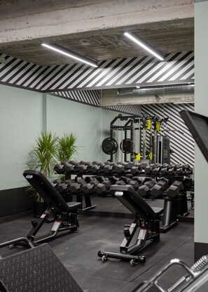 Un gimnasio con equipo de ejercicio, incluyendo mancuernas y cintas de correr.