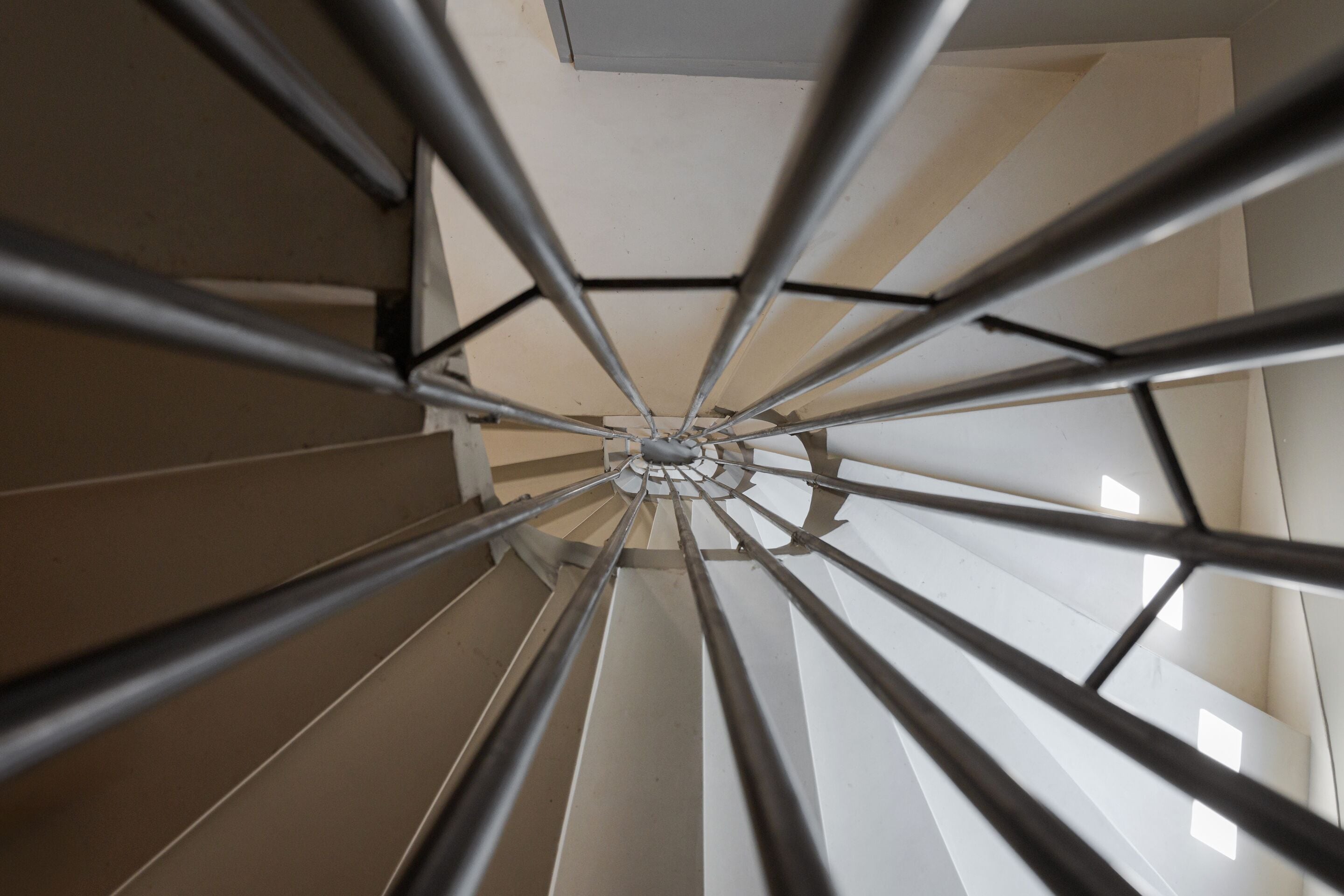 A spiral staircase with metal railings and a white interior.