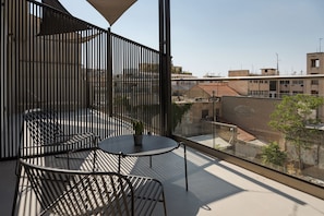 A balcony with a table and chairs, a potted plant, and a view of the cityscape. - Noctilia Athens (Athens)