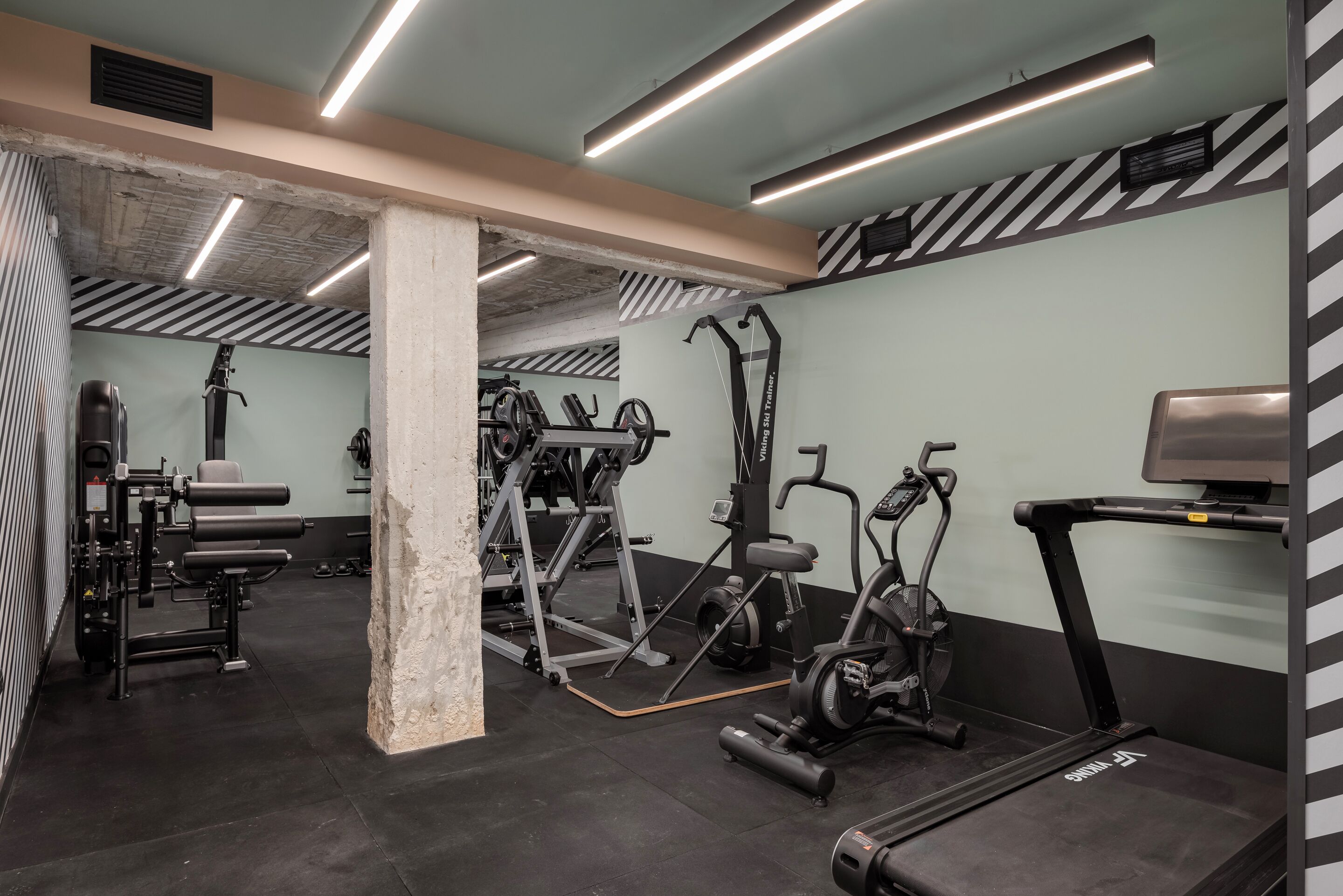 Et fitnesscenter med forskellig træningsudstyr, herunder løbebånd og styrkemaskiner.