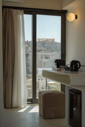 A room with a large window, a kitchenette, and a view of a historical building. - Noctilia Athens (Athens)