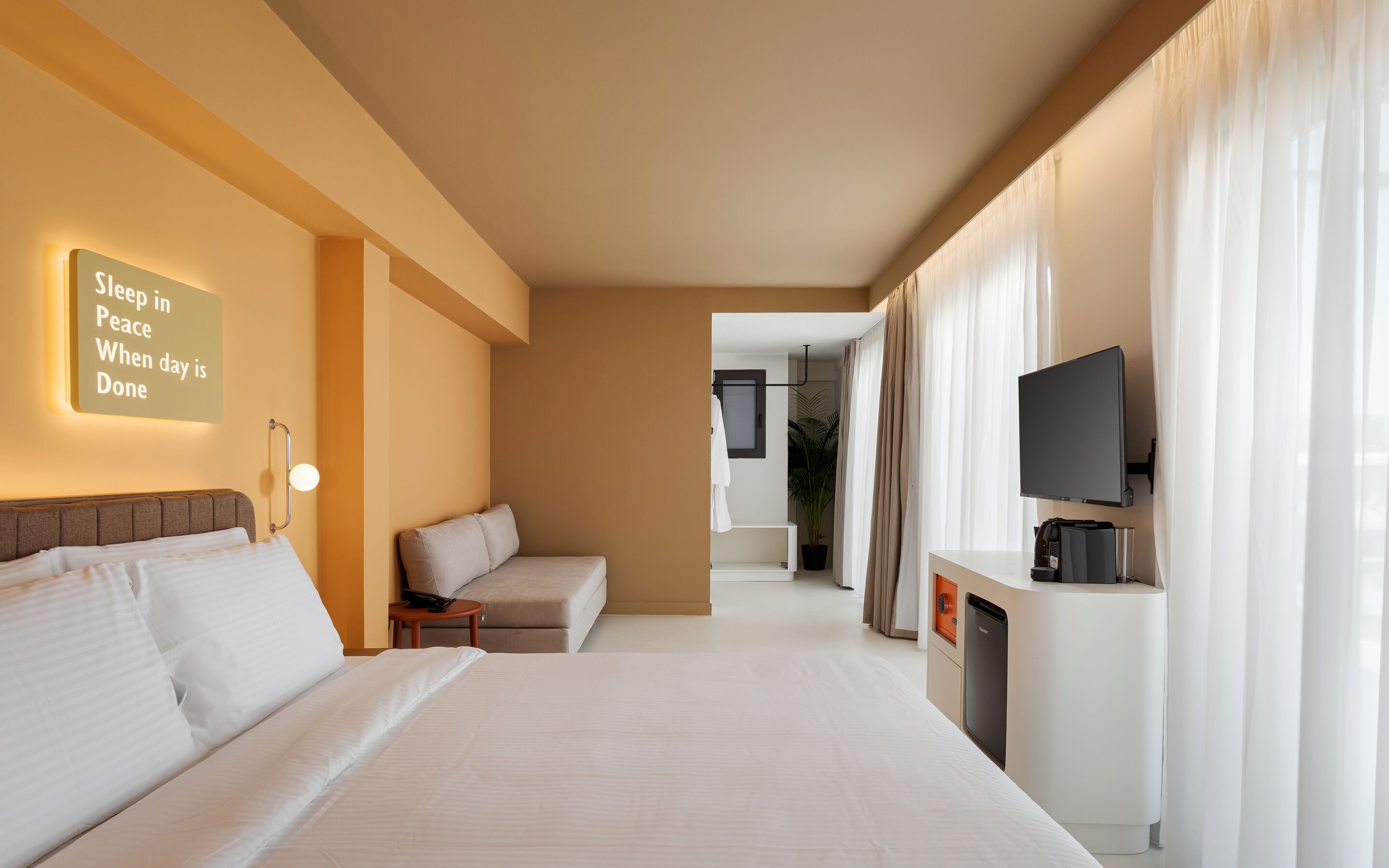Una habitación de hotel con cama, sofá, televisor y cafetera.